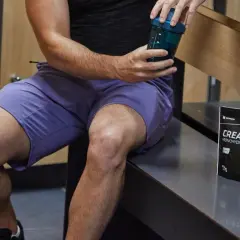 Un homme prépare sa boisson post-entraînement avec de la créatine. Elle sert à améliorer la performance et la récupération musculaire.