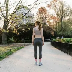 Femme en tenue de sport marchant dans un parc, une façon naturelle de muscler son périnée en profitant du grand air.