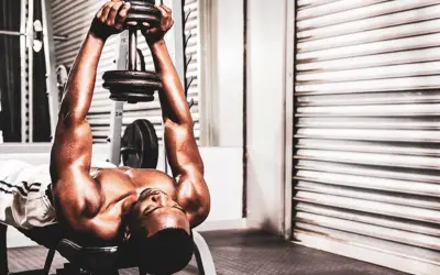 Un homme fait un exercice de pull over muscu avec un haltère sur un banc de musculation.