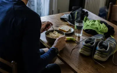 Préparation pour un semi-marathon : un bol de flocons d'avoine aux bananes, une tranche de pain, une banane, une verre d'eau, des chaussures de course et des vêtements.