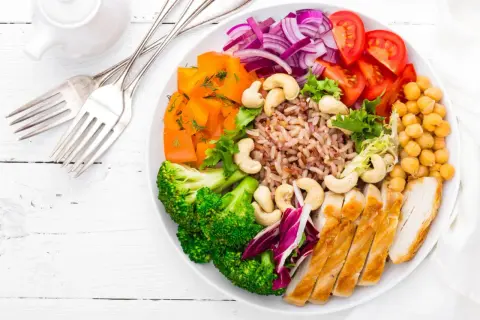 Un plat coloré avec poulet, riz brun, brocolis, carottes, tomates, oignons rouges et pois chiches. Une belle façon de manger sain et pas cher.