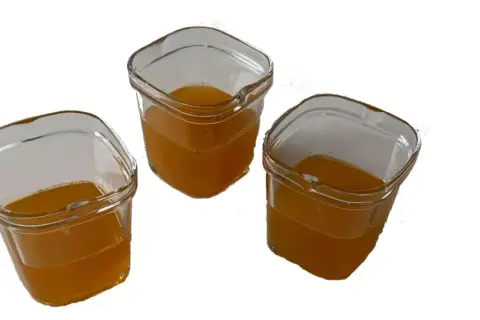 Trois petits pots en verre remplis d'un liquide ambré, prêts à être consommés comme gel énergétique maison.