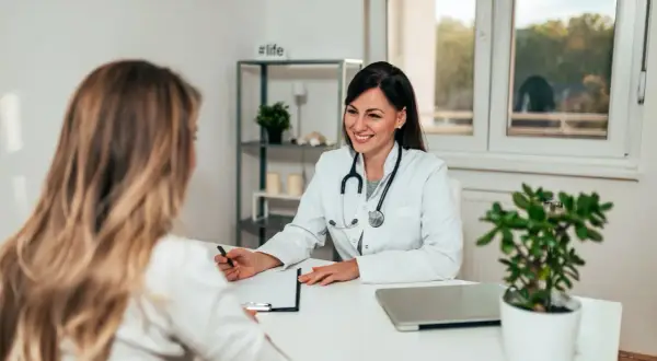 Sage-femme souriante discutant avec une patiente, évoquant une possible rééducation périnée.