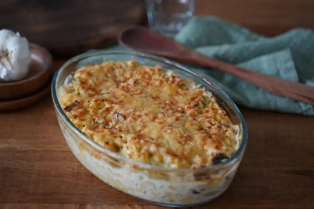 Gratin de pâtes au fromage, une option pour manger sain et pas cher. Une tête d'ail est visible à gauche.