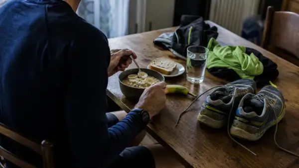 Préparation pour un semi-marathon : un bol de flocons d'avoine aux bananes, une tranche de pain, une banane, une verre d'eau, des chaussures de course et des vêtements.