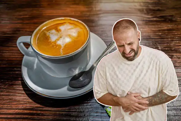 Un homme se tient le ventre, visiblement souffrant, à côté d'une tasse de café. Il semble que boire beaucoup de café lui ait causé des maux d'estomac.