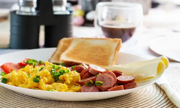 Un délicieux petit déjeuner sain avec des œufs brouillés, des saucisses, des toasts et du fromage.