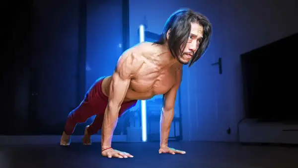 Un homme musclé en position de pompe, pratiquant la musculation poids du corps dans une pièce sombre éclairée par des lumières bleues.