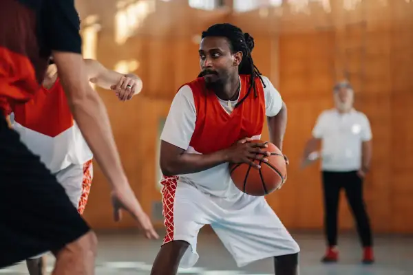 Un joueur de basket concentré, ballon en main, en plein match. Le basket fait-il grandir ? Peut-être pas en taille, mais en esprit d'équipe !